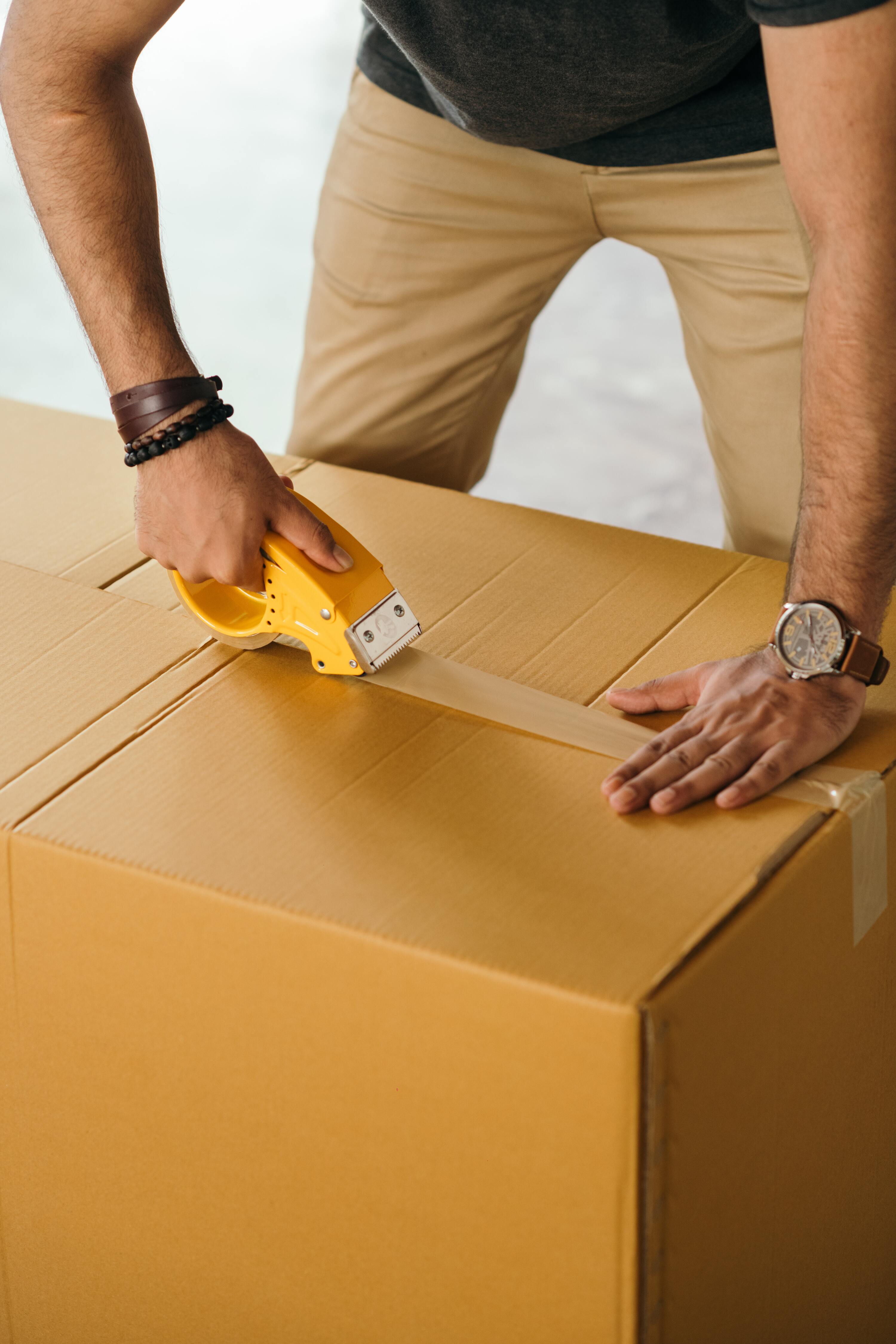 Un homme s'occupeant de l'emballage de ses affaires pour limiter les coûts de son déménagement