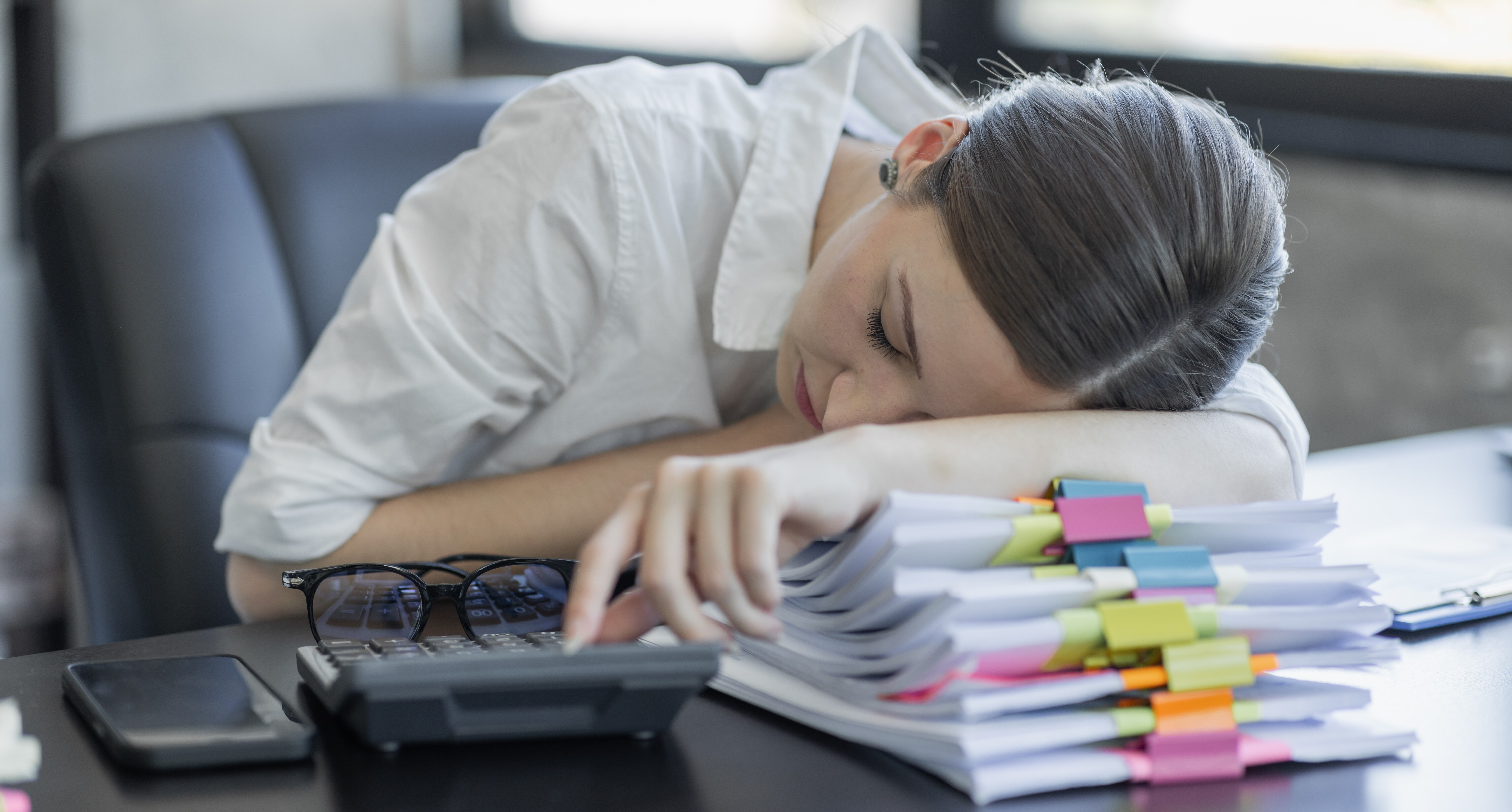 une femme écroulée sur son bureau, fatiguée par les démarches à suivre.